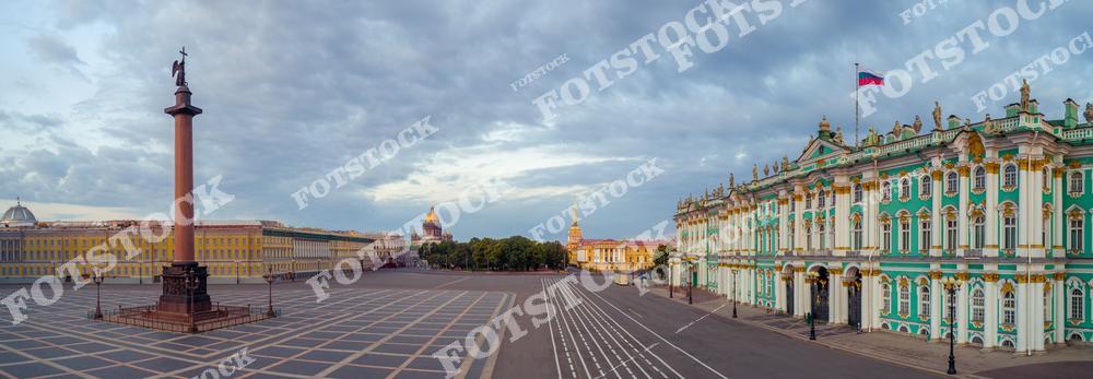 Фотография панорамного вида Санкт-Петербург, Россия, сделанная в пасмурный день. На изображении показана Дворцовая площадь с Александровская колонна в центре композиции. В кадре также виден Зимний дворец, в котором расположен Государственный Эрмитаж. Фотоснимок передаёт масштаб исторического центра города, строгую архитектуру и атмосферу северной столицы. Это изображение отражает панораму Дворцовой площади и улиц Санкт-Петербурга как одного из главных культурных символов России.